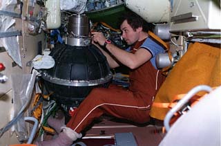 Mir-18 commander Vladimir N. Dezhurov is photographed preparing to install new gyrodynes in the Kristall module. 